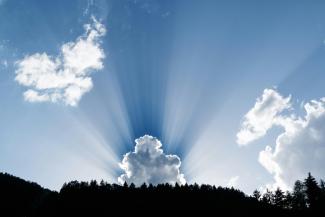 Blue sky with sun rays bursting from behind a cloud